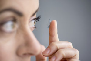 Attractive mature lady putting on contact lenses in her eyes