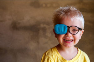 Portrait of funny child in new glasses with patch