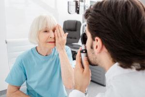 Senior woman patient checking vision in optician's office. 